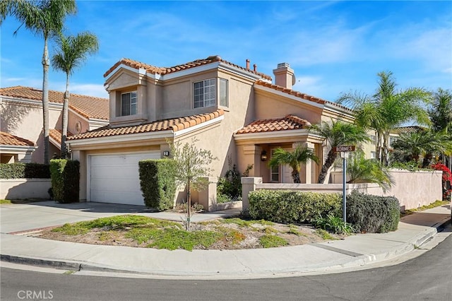 mediterranean / spanish-style house featuring stucco siding, fence, concrete driveway, a garage, and a chimney