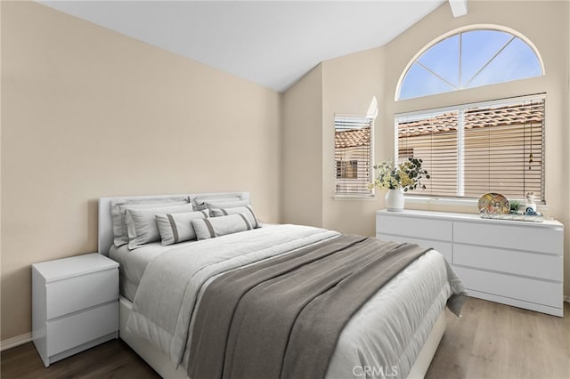 bedroom featuring vaulted ceiling, multiple windows, and wood finished floors