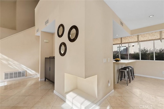 hall with tile patterned floors, visible vents, and baseboards