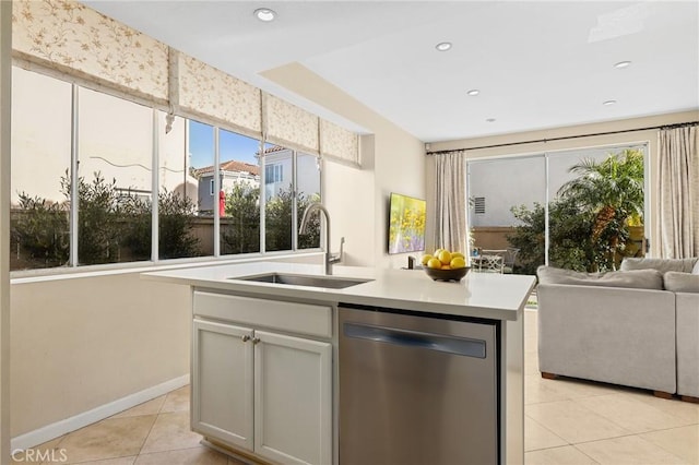 kitchen with a sink, open floor plan, light tile patterned floors, a healthy amount of sunlight, and dishwasher