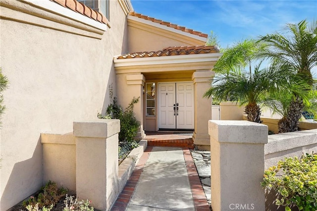 entrance to property featuring a tiled roof and stucco siding