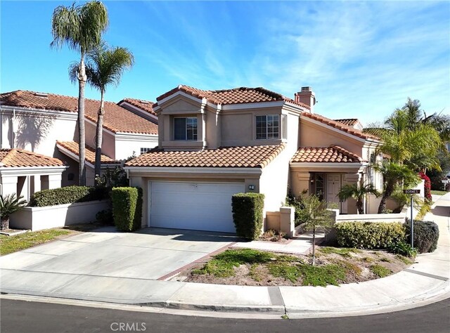 mediterranean / spanish-style house with stucco siding, a tile roof, driveway, and a chimney