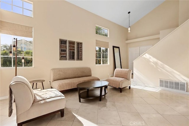 living area featuring light tile patterned floors, visible vents, high vaulted ceiling, and baseboards