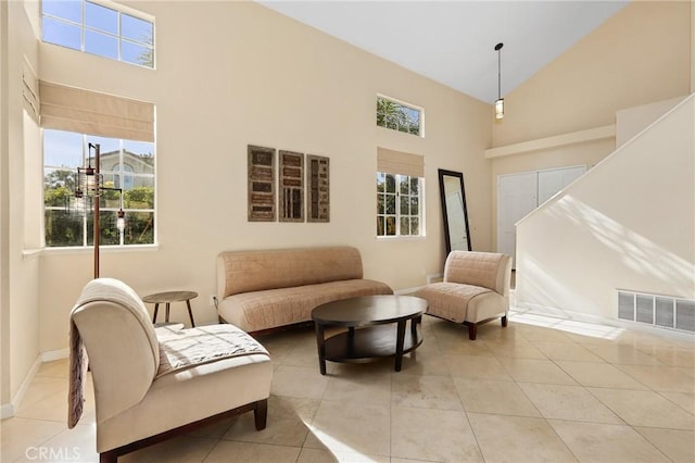 interior space with light tile patterned floors, visible vents, baseboards, and high vaulted ceiling