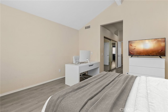 bedroom with visible vents, baseboards, beamed ceiling, wood finished floors, and a closet