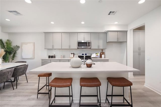 kitchen featuring stainless steel appliances, gray cabinetry, and visible vents