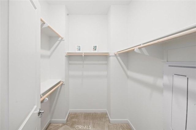 spacious closet featuring light carpet and a heating unit