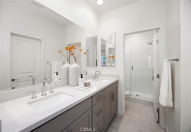 bathroom featuring a shower stall, toilet, double vanity, and a sink