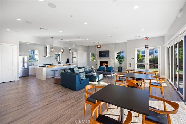 dining space featuring visible vents, recessed lighting, french doors, a fireplace, and light wood finished floors