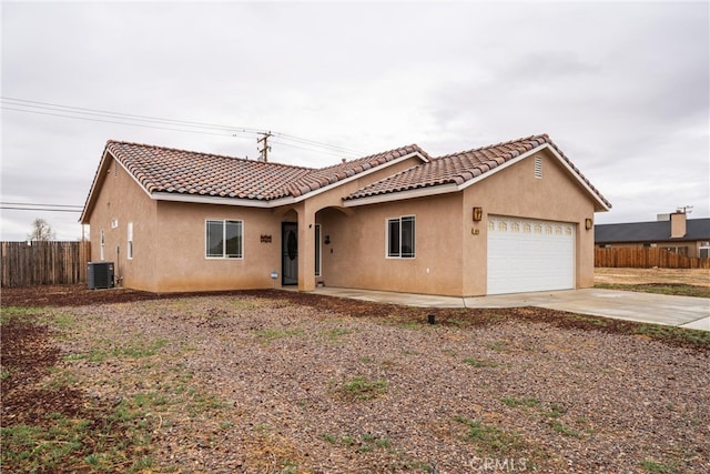 view of front facade with central AC unit, fence, driveway, stucco siding, and a garage