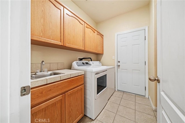 laundry area with washing machine and dryer, light tile patterned floors, cabinet space, and a sink