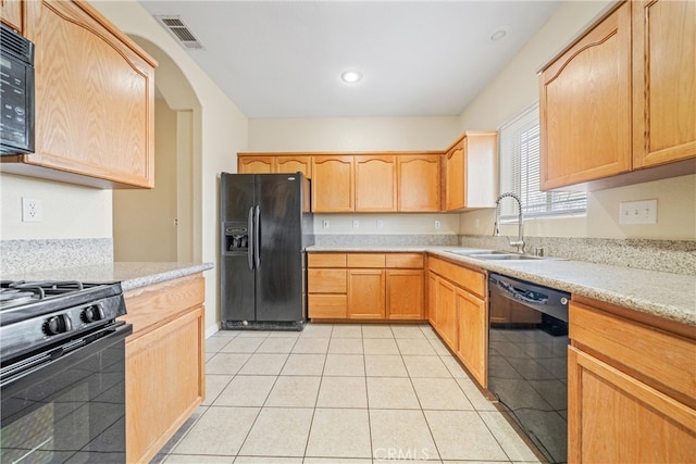 kitchen featuring black appliances, light brown cabinetry, a sink, light countertops, and light tile patterned floors