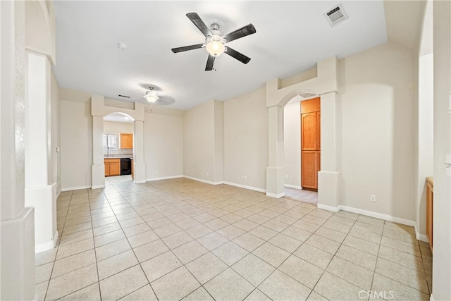 empty room with visible vents, arched walkways, light tile patterned flooring, baseboards, and ceiling fan