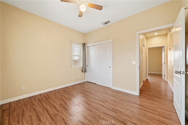 unfurnished bedroom with a ceiling fan, baseboards, visible vents, light wood finished floors, and a closet