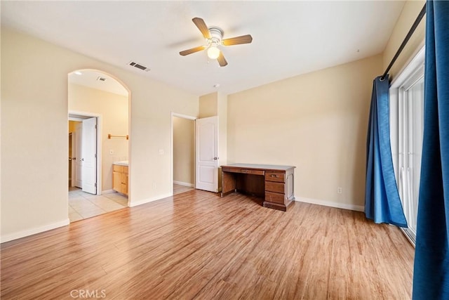 interior space featuring visible vents, ceiling fan, baseboards, light wood-style floors, and arched walkways