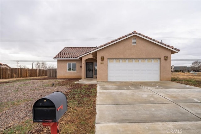 view of front facade with an attached garage, fence, a tile roof, stucco siding, and driveway