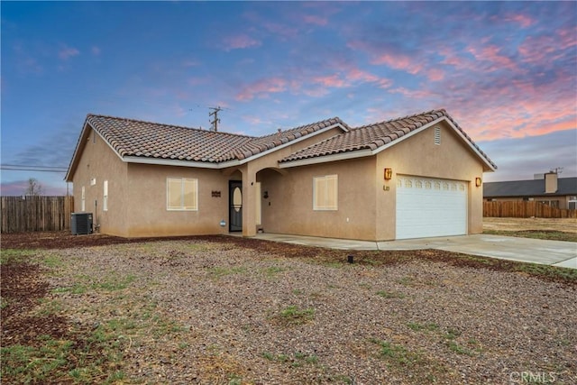 view of front facade with stucco siding, central AC, fence, concrete driveway, and a garage