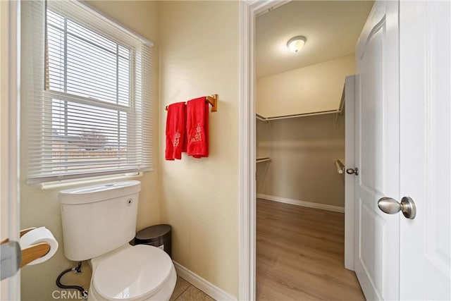 bathroom with toilet, baseboards, and wood finished floors