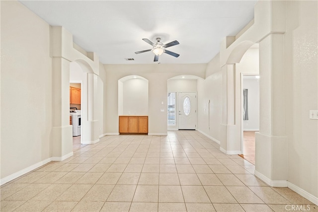 empty room featuring visible vents, washer / clothes dryer, light tile patterned flooring, arched walkways, and ceiling fan