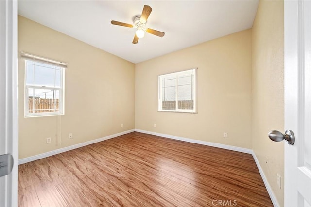 empty room with ceiling fan, baseboards, and wood finished floors