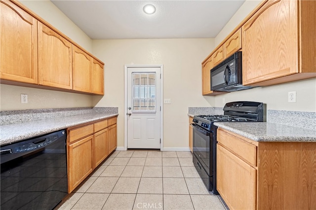 kitchen with black appliances, light tile patterned floors, light brown cabinets, and baseboards