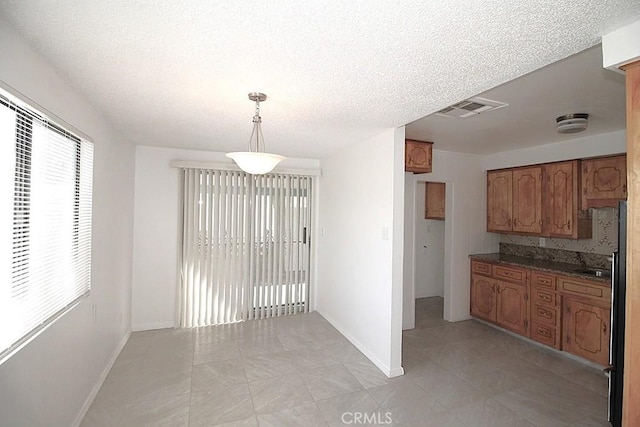 1111 Taos Dr, Barstow, CA 92311 - kitchen with brown cabinets, baseboards, decorative light fixtures, light tile patterned flooring, and a textured ceiling