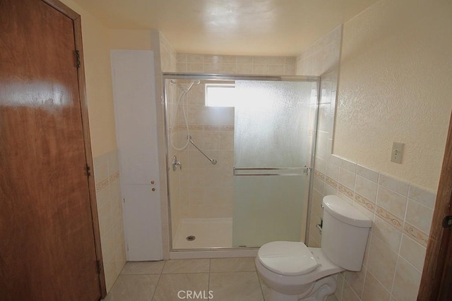 1111 Taos Dr, Barstow, CA 92311 - full bath with tile walls, toilet, a stall shower, tile patterned flooring, and a wainscoted wall