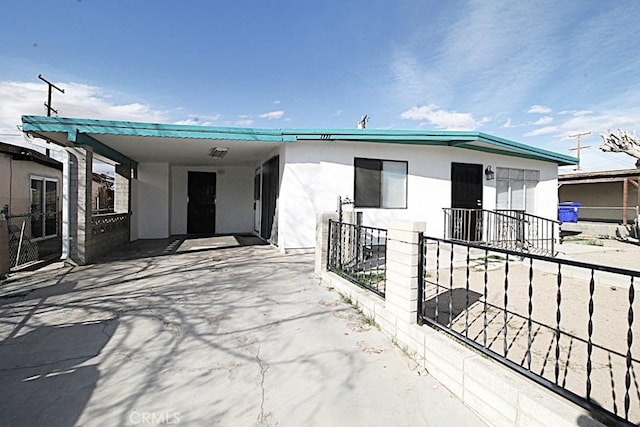 view of front of property with stucco siding, an attached carport, and driveway