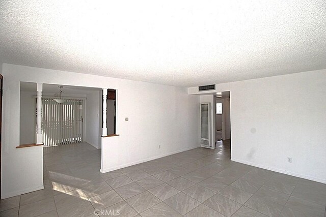 1111 Taos Dr, Barstow, CA 92311 - tiled spare room featuring a textured ceiling, a heating unit, and baseboards