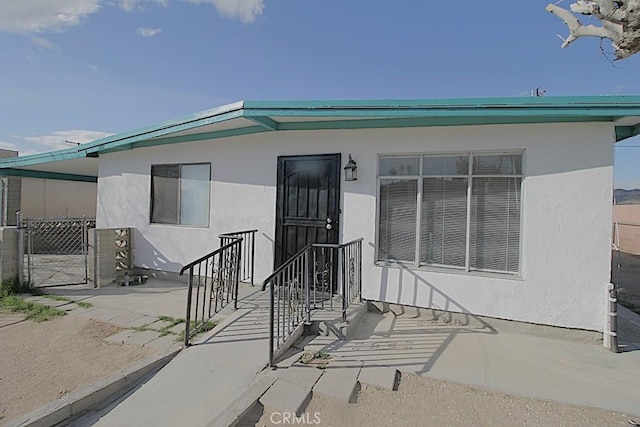 view of exterior entry with a gate and stucco siding