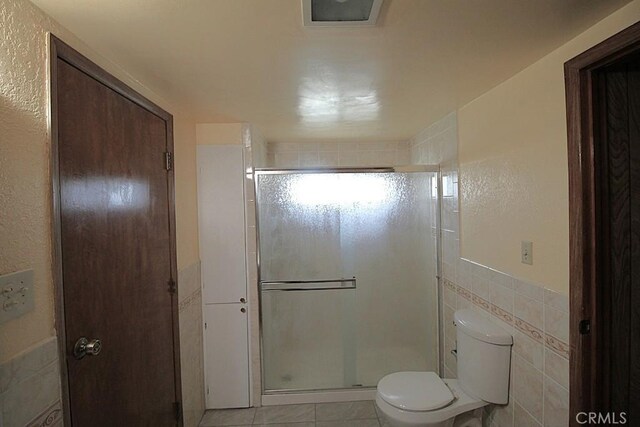 1111 Taos Dr, Barstow, CA 92311 - full bathroom with a stall shower, toilet, tile walls, and tile patterned floors