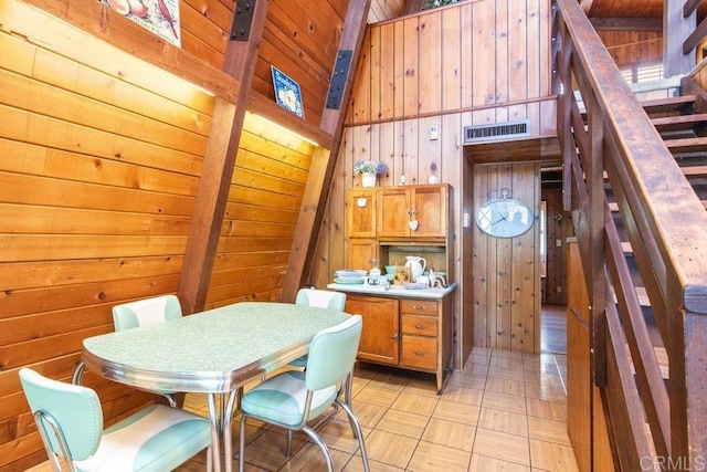 dining area with visible vents, high vaulted ceiling, wood walls, wooden ceiling, and stairs