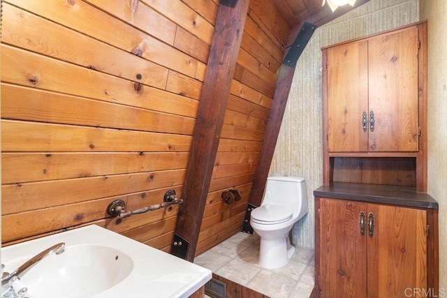 bathroom featuring wood walls, toilet, and a sink