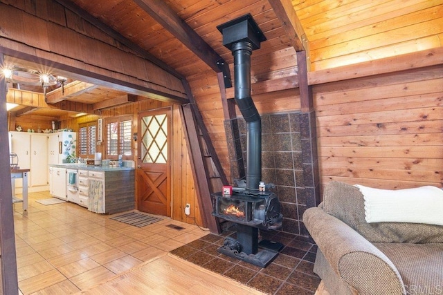 living room featuring beam ceiling, wooden walls, wooden ceiling, and a wood stove