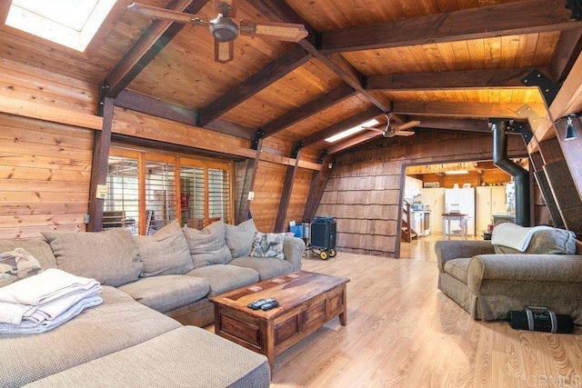 living area with wood finished floors, a ceiling fan, vaulted ceiling with skylight, wood ceiling, and wood walls