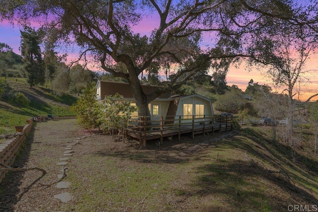 back of property at dusk with a wooden deck