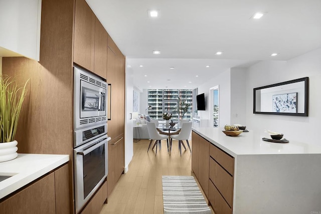 kitchen with light countertops, modern cabinets, light wood-type flooring, and appliances with stainless steel finishes