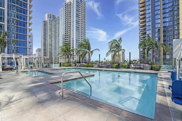 community pool with a city view, an outdoor living space, and a patio area