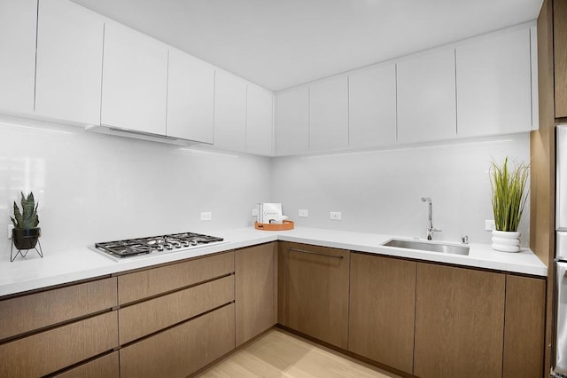 kitchen with light countertops, a sink, and stainless steel gas stovetop
