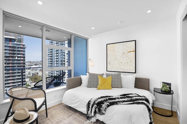 bedroom with recessed lighting, baseboards, a view of city, and wood finished floors