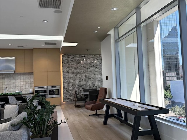 interior space featuring backsplash, light wood finished floors, open floor plan, visible vents, and oven