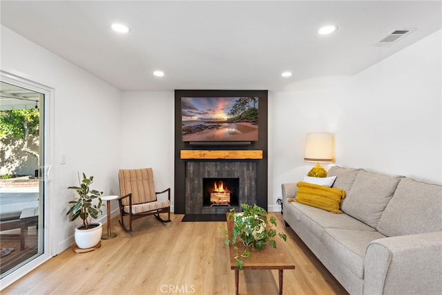 living area with visible vents, recessed lighting, a large fireplace, and wood finished floors