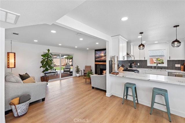 kitchen with visible vents, a healthy amount of sunlight, decorative backsplash, light wood-style floors, and white cabinetry