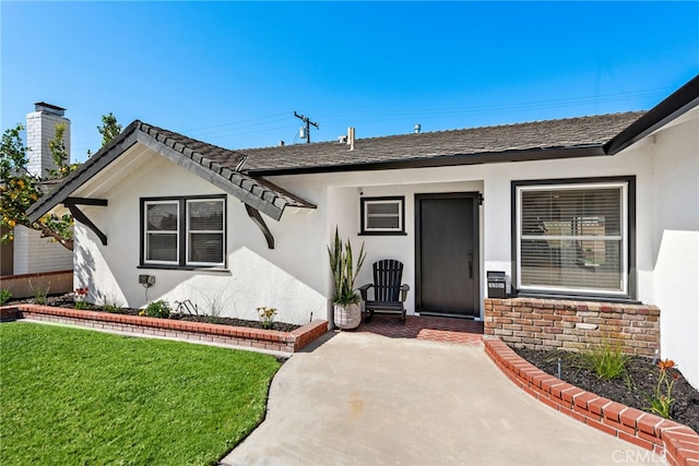 property entrance featuring stucco siding, a chimney, and a yard