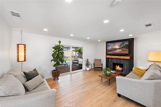 living area featuring recessed lighting, visible vents, light wood-style flooring, and a large fireplace