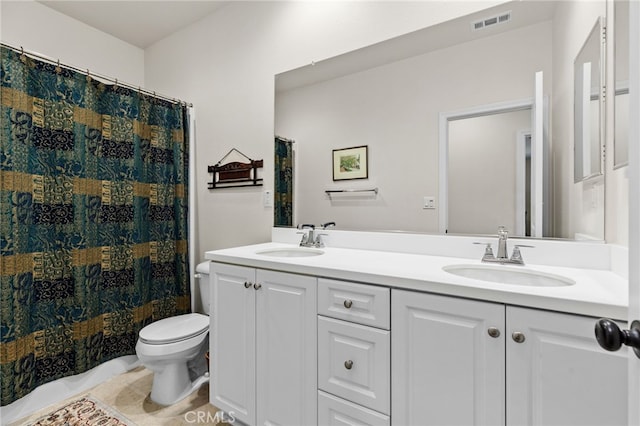 bathroom featuring double vanity, visible vents, toilet, and a sink