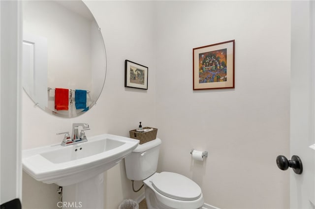 bathroom featuring toilet, baseboards, and a sink