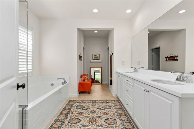 full bath featuring tile patterned flooring, double vanity, a garden tub, and a sink