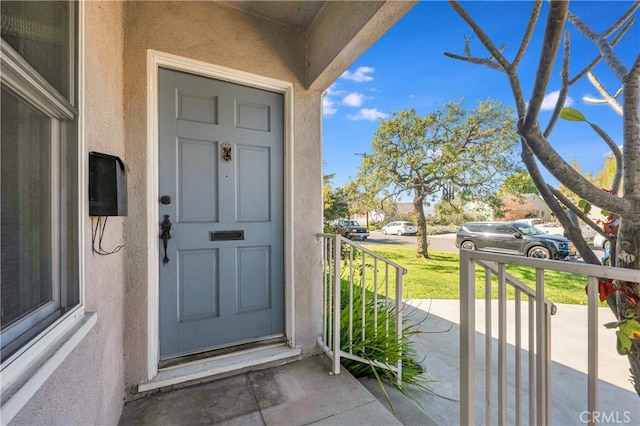 doorway to property with covered porch and stucco siding