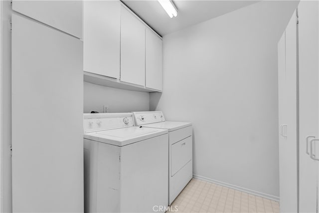 clothes washing area featuring baseboards, cabinet space, light floors, and washer and clothes dryer